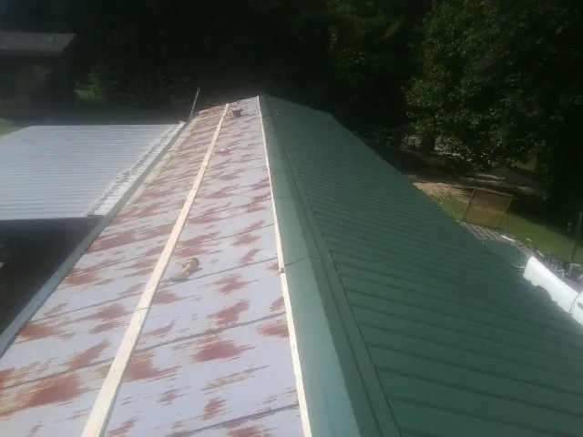 Old rusted panels beside newly installed green metal roofing — Wind Damage Roof Repair by Roofing Brothers in Kenton