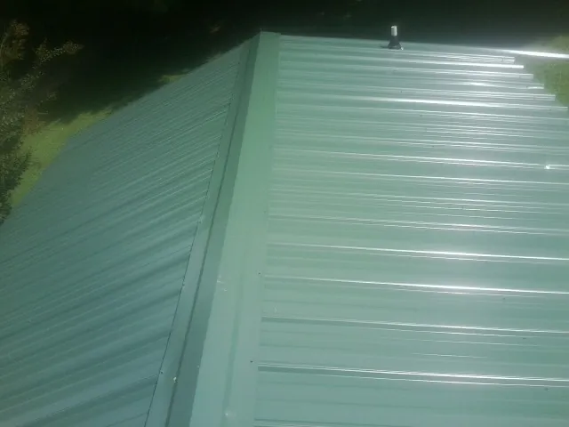 New green metal panels meeting at the ridge of a roof — Flat Roof Repair work by our crew in Kenton