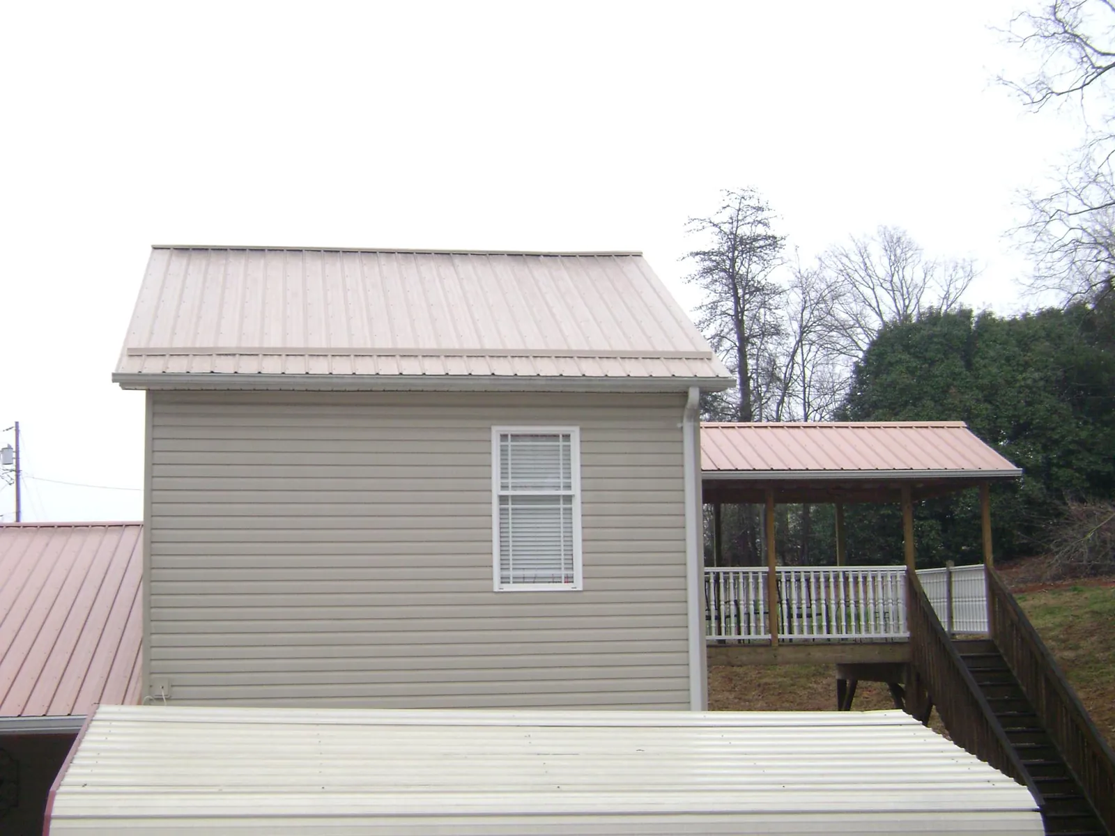Tan metal roofs on a two story addition and attached porch, from a Roof Replacement job in Kenton